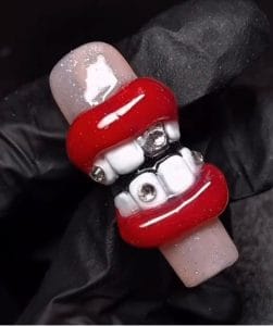 3D nail art with red lips, white teeth, and silver gems